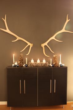 two deer antlers on top of a cabinet with candles