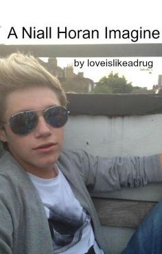 a young man sitting on top of a wooden bench next to a wall wearing sunglasses