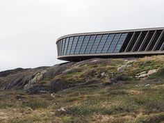 a building on top of a hill with grass and rocks around it's sides