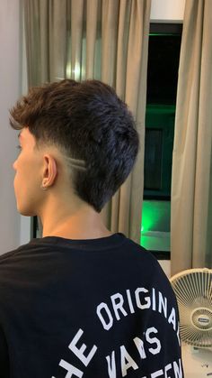 a young man is looking out the window with his hair combed back and undercut