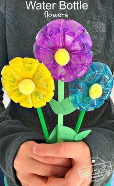 a person holding three plastic flowers in their hands with the words water bottle flowers on them