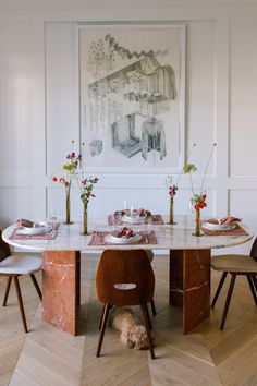 a dining room table with two chairs and a dog sitting on the floor in front of it