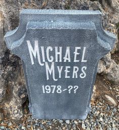 a headstone for michael myers is shown in front of a rock wall and tree