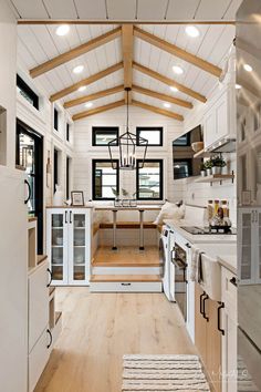 the interior of a tiny home with wood flooring and white walls, wooden beams