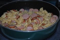 a pan filled with pasta and sausage on top of a stove