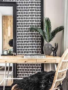 a black and white patterned wall in a living room next to a table with a plant on it