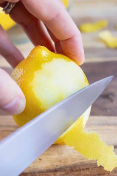 a person is slicing an orange with a knife on a cutting board next to some lemons