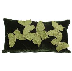 a green velvet pillow with leaf appliques on it