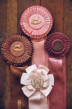 three ribbons and two rosettes on top of each other, one with a horse