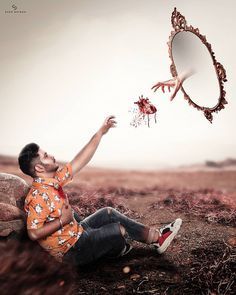 a man sitting on the ground in front of a mirror throwing something into the air