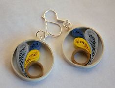 the earrings are made out of paper and have yellow, blue and grey swirls