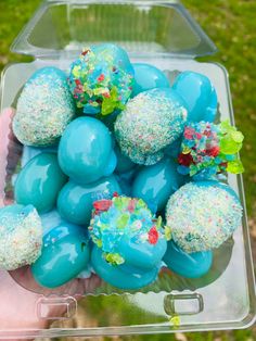 a person holding a plastic container filled with blue and white cake balls