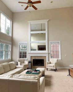 a living room with couches, chairs and a fire place in the middle of it