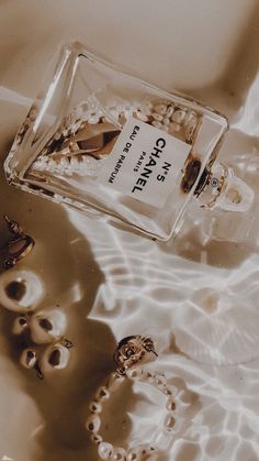 a bottle of chanel perfume sitting on top of a table next to some pearls