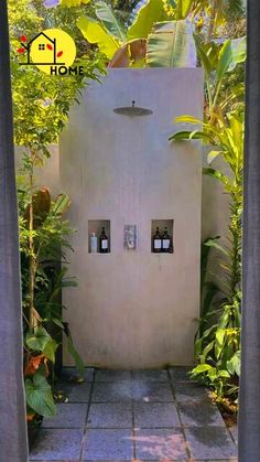 an outdoor shower in the middle of some trees and bushes with two lights on each side