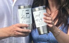 a man and woman holding up two cups with the names of their loved ones written on them