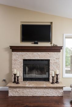 a living room with a fireplace, television and candles on the mantel in front of it