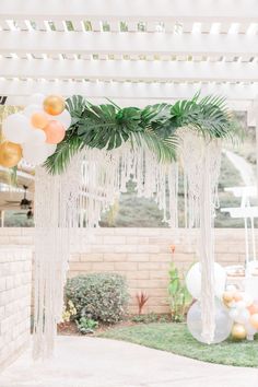 an outdoor party with balloons, streamers and palm leaves