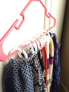 a rack with clothes hanging on it next to a wall and a window in the background