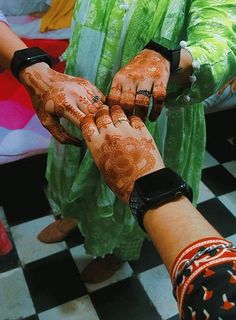 two people holding hands with hendi tattoos on their palms and arms, both wearing wristbands