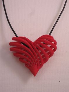 a red heart shaped necklace hanging from a black cord