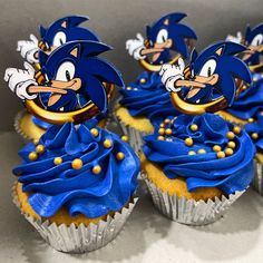 three cupcakes with blue frosting decorated like sonic the hedgehog characters on top