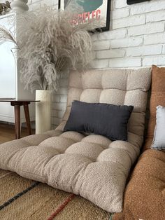 a couch that is sitting in front of a white brick wall with some plants on it