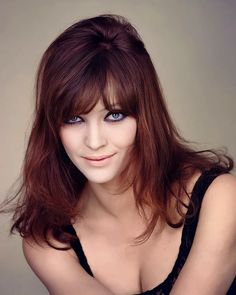 a woman with long hair and blue eyes posing for the camera, wearing a black top