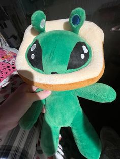 a person holding a green stuffed animal in their hand