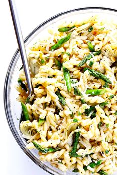 a bowl filled with pasta and asparagus on top of a white tablecloth