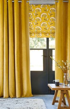 a living room with yellow curtains and a white rug