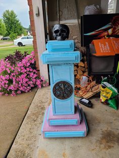 a blue and pink clock sitting on top of a wooden stand in front of a house