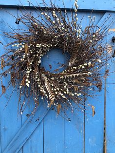 a blue door with a wreath hanging on it's side and dried flowers in the middle