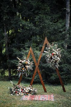 an outdoor ceremony setup with flowers and greenery on the grass in front of trees