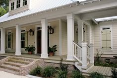 a white house with columns and plants on the front porch