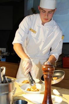 a person in a chef's uniform is preparing food on plates and serving utensils