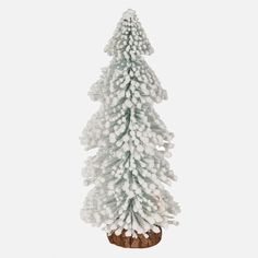 a small white christmas tree sitting on top of a wooden stand