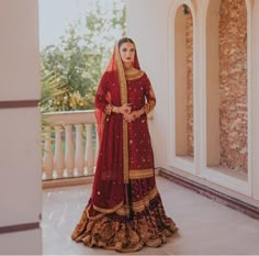 a woman in a red and gold bridal gown standing on a balcony with an archway