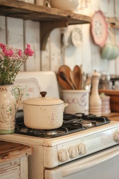 a white stove top oven sitting in a kitchen next to a wooden shelf filled with pots and pans