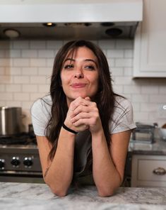 a woman sitting at a kitchen counter with her hands on her face and looking up