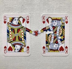 two playing cards with the king and queen holding hands