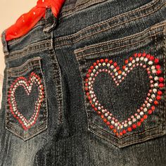 a pair of jeans with hearts painted on the back pocket and red ribbon tied around the waist