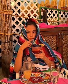 a woman sitting at a table holding a drink