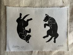 two black and white images of cats on a piece of cloth