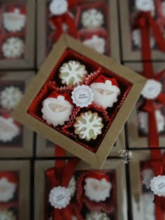 four decorated cupcakes in a box with red ribbon and snowflakes on them