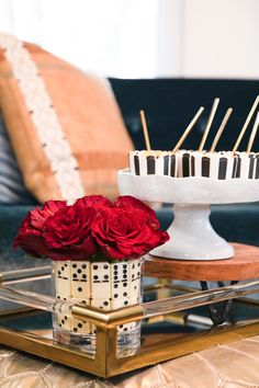 the cake is decorated with black and white stripes, red roses, and wooden skewers