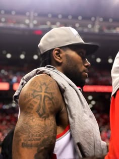 a man with a cross tattoo on his arm standing in front of a crowd at a basketball game