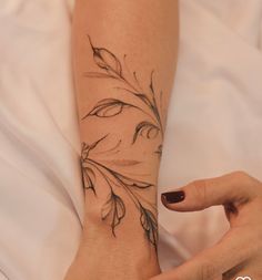 a woman's arm with a flower tattoo on the left side of her hand