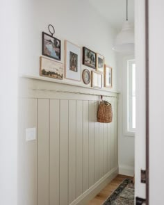 a hallway with white paneling and pictures on the wall