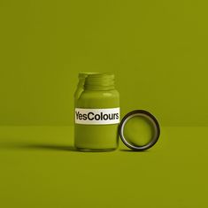 a green bottle with the word yescolours on it next to a black ring